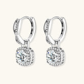 Sterling silver twisted hoop earrings with round moissanite stones in halo settings against neutral background.