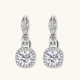 Sterling silver twisted hoop earrings with round moissanite stones in halo settings against neutral background.