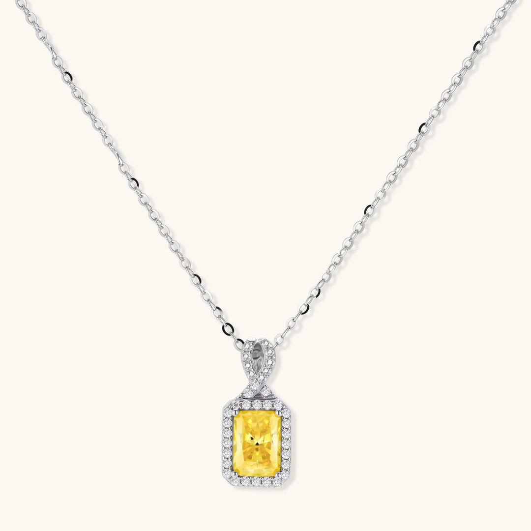 Yellow moissanite jewelry set with emerald-cut stones in sterling silver halo settings on white background.