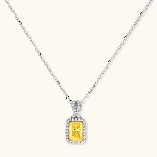 Yellow moissanite jewelry set with emerald-cut stones in sterling silver halo settings on white background.