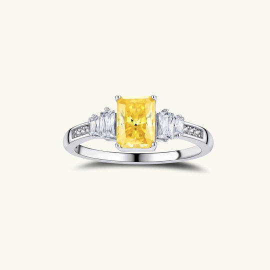 Yellow moissanite jewelry set with emerald-cut stones in sterling silver halo settings on white background.