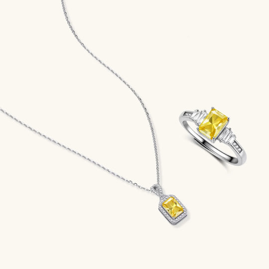 Yellow moissanite jewelry set with emerald-cut stones in sterling silver halo settings on white background.