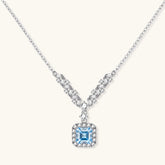 Sterling silver necklace with geometric crystal arrangement forming a V-shape and square blue moissanite centerpiece pendant