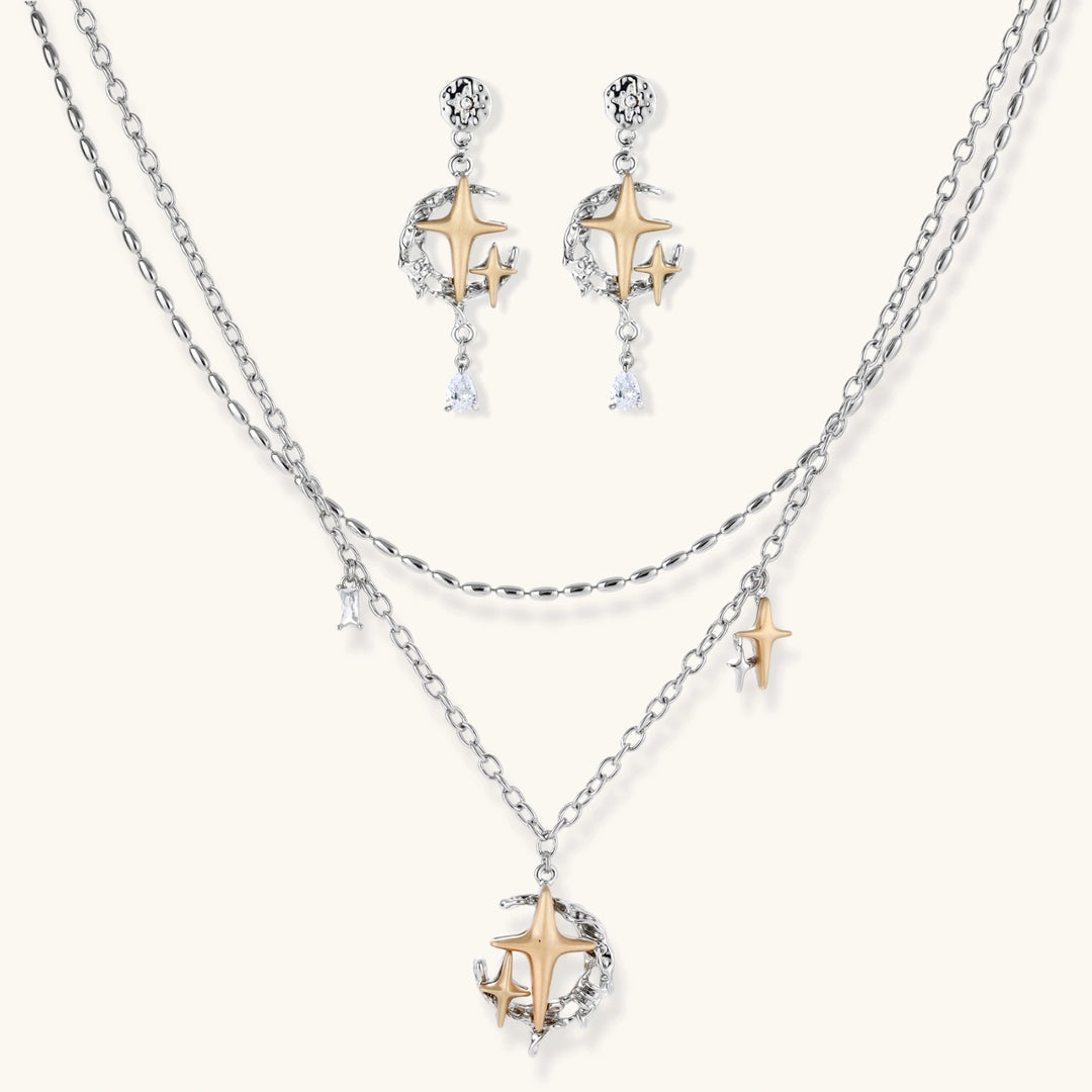 Delicate eco-brass jewelry set featuring gold star and silver moon crescents with clear zirconia crystal drops on cream background