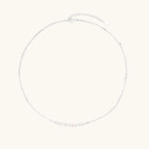 Delicate sterling silver chain necklace with small freshwater pearls arranged in a curved smile arc on cream background.