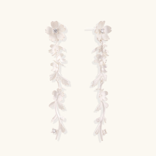 Long sterling silver drop earrings with delicate floral vine design and crystal accents on white background