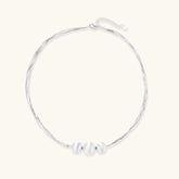 Sterling silver multi-strand necklace with three brushed round beads on cream background