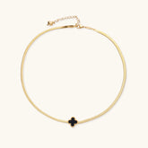 Dainty 18K gold-plated herringbone chain necklace with black enamel quatrefoil clover pendant on white background