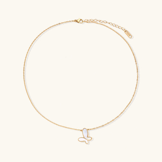 Gold-plated butterfly pendant with iridescent mother of pearl inlay on delicate chain against cream background.