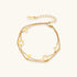 Double-layer gold-plated bracelet with quatrefoil and star charms on cream background, 18K gold finish.
