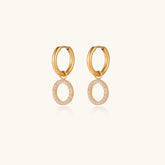 Gold-plated huggie hoop earrings with CZ-studded open circle charms on beige background