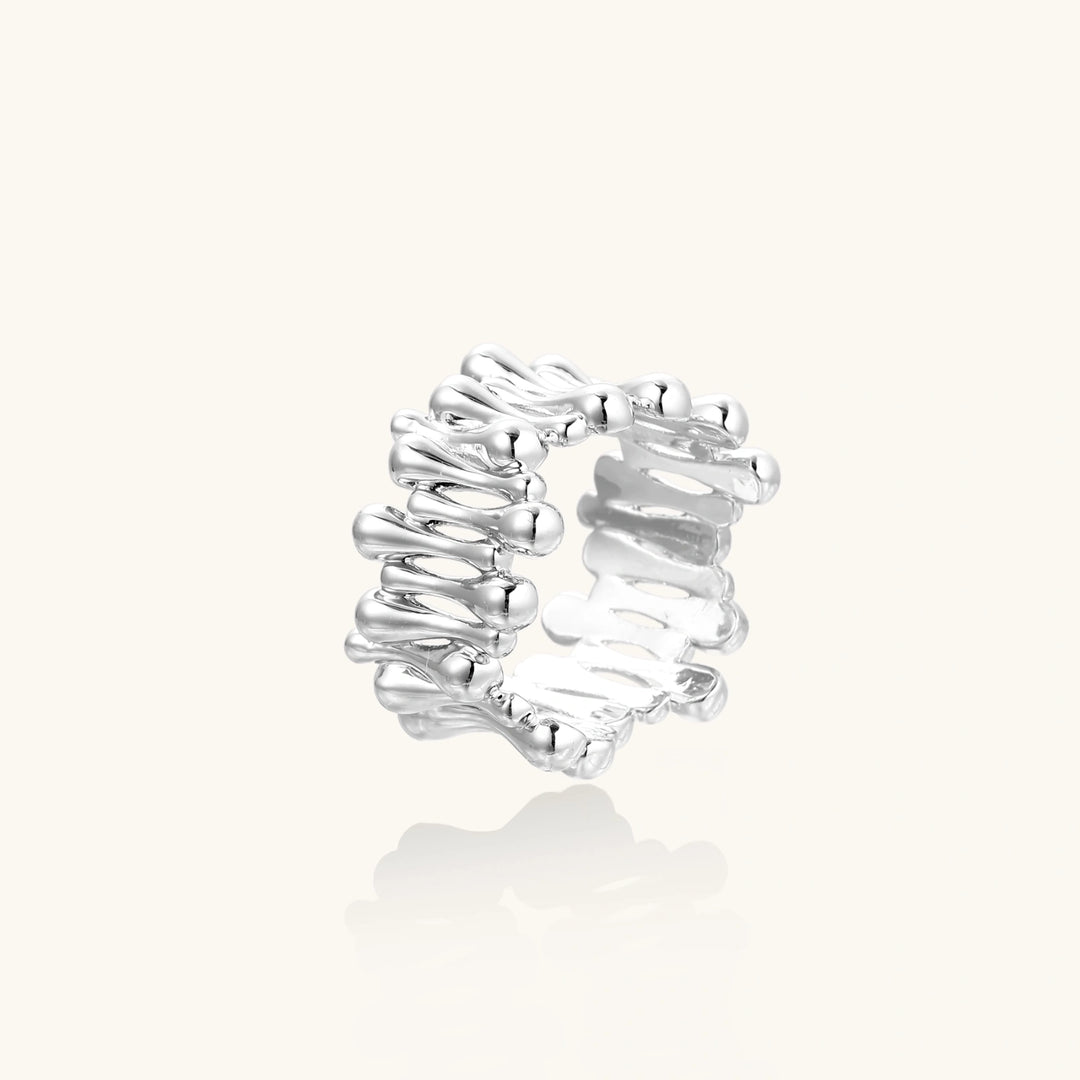 Wide band ring with sculptural wave ripples in polished white gold plated eco-brass on cream background