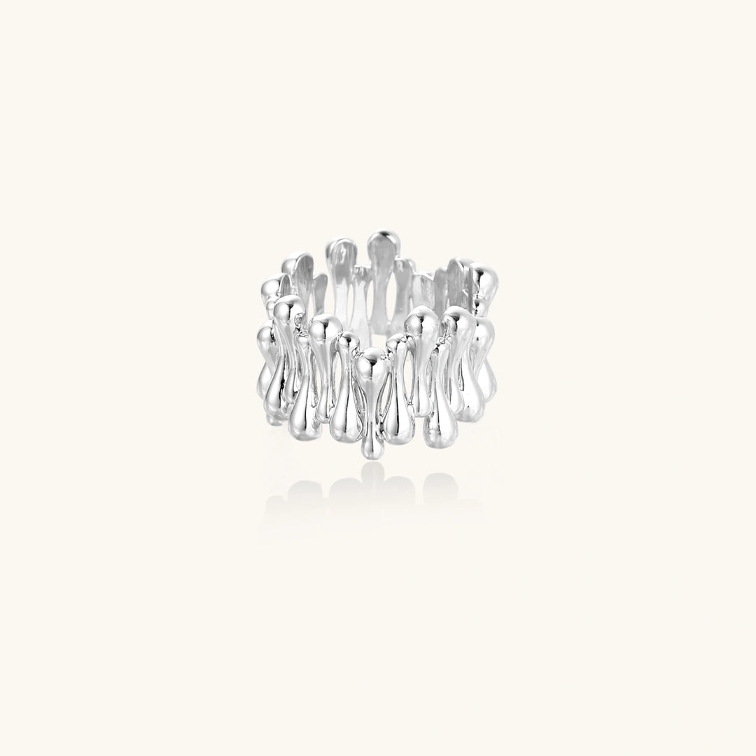 Wide band ring with sculptural wave ripples in polished white gold plated eco-brass on cream background