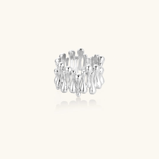 Wide band ring with sculptural wave ripples in polished white gold plated eco-brass on cream background