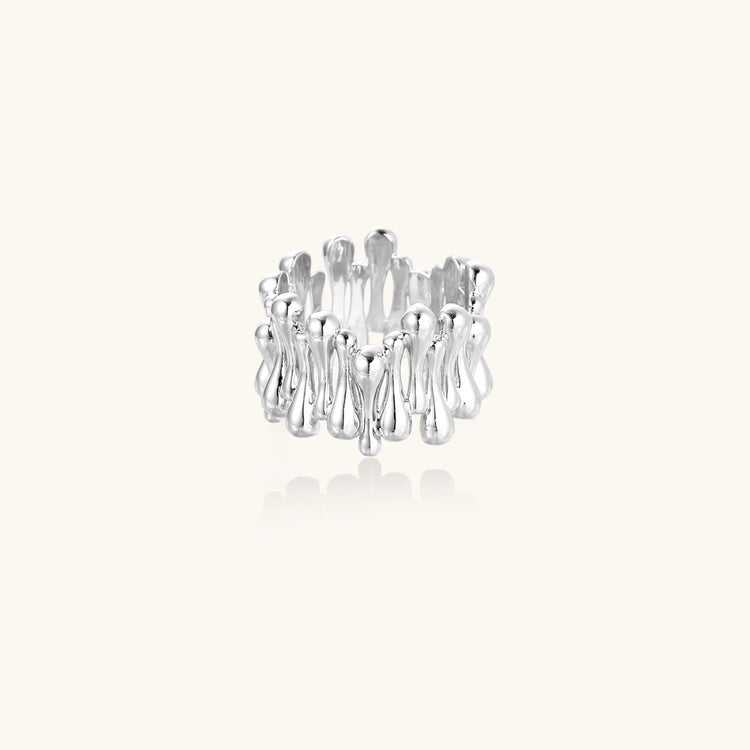 Wide band ring with sculptural wave ripples in polished white gold plated eco-brass on cream background