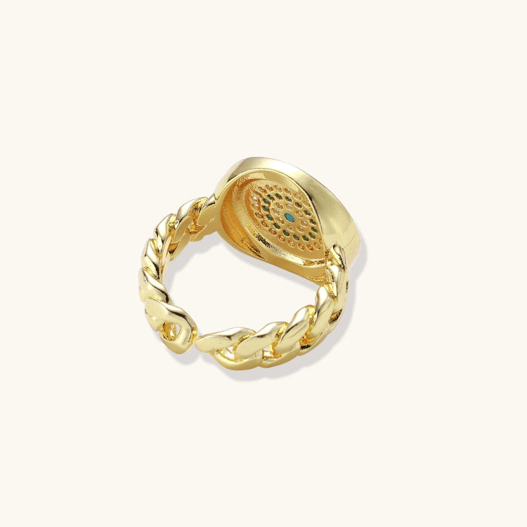 Gold chain ring with Greek key border and turquoise evil eye center on white background