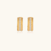 Textured gold huggie hoop earrings with raised ribbed rows creating dimensional sculptural design on cream background
