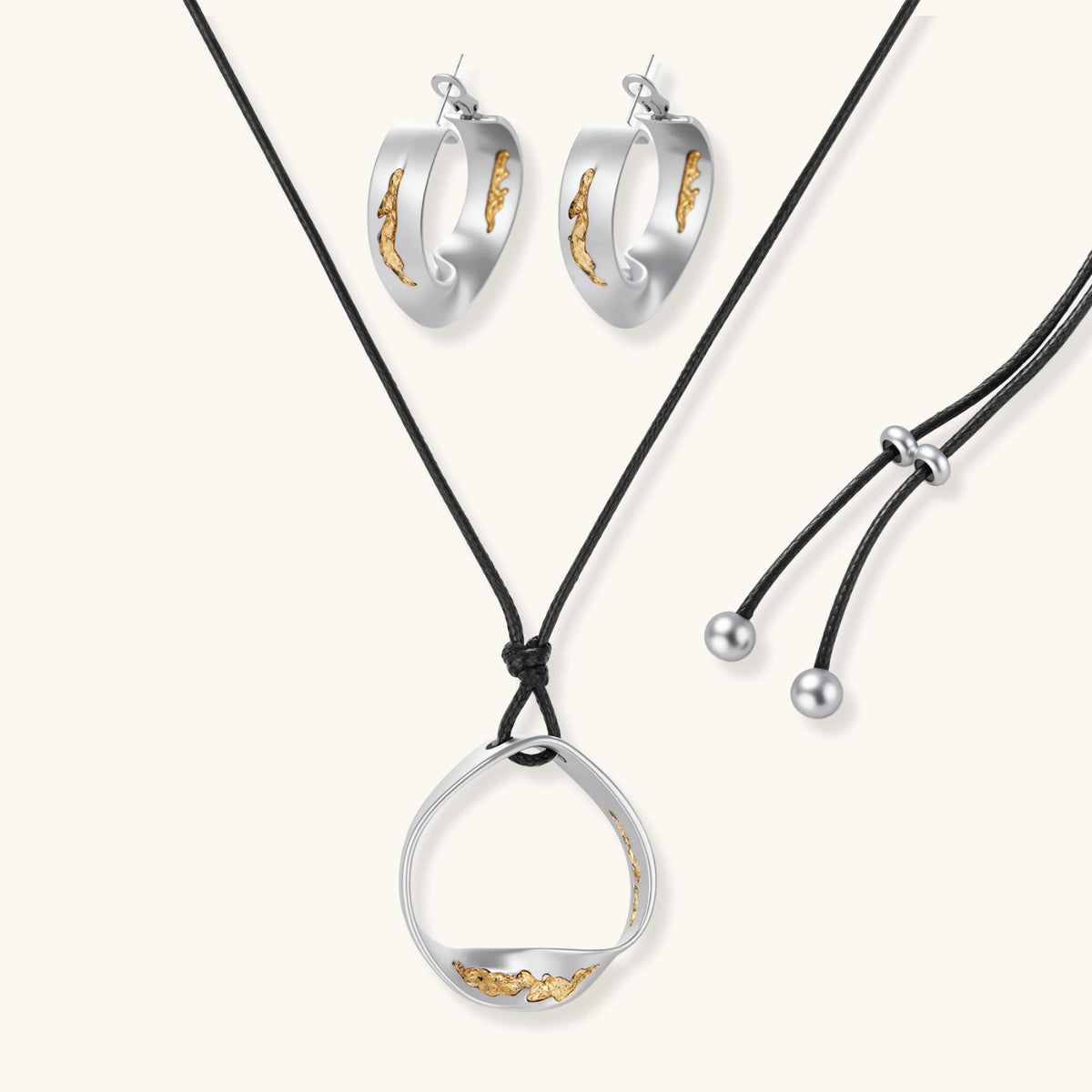 Artistic jewelry set featuring curved silver pendant with gold veining on black cord plus matching asymmetrical hoop earrings