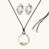 Artistic jewelry set featuring curved silver pendant with gold veining on black cord plus matching asymmetrical hoop earrings