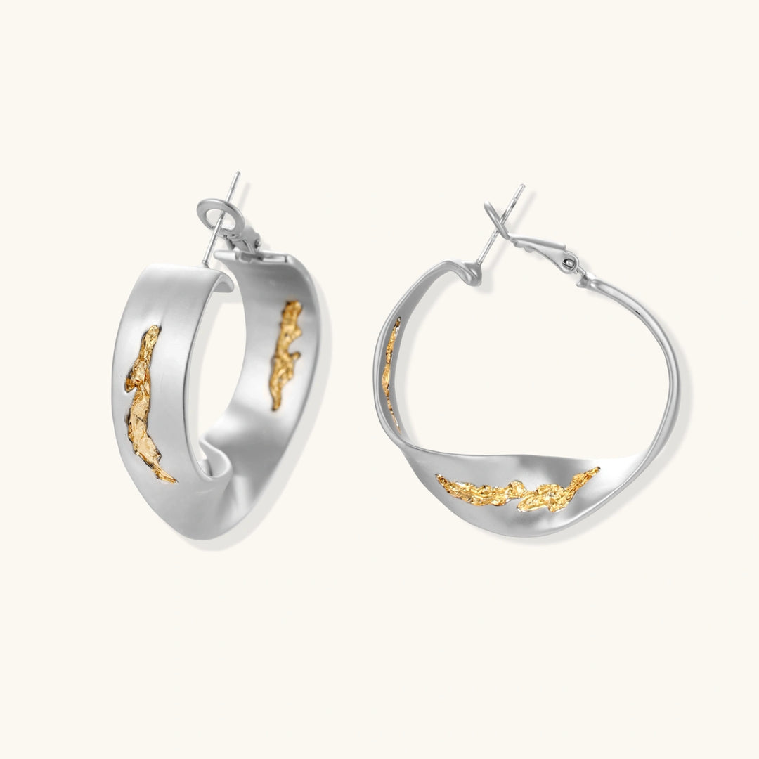 Artistic jewelry set featuring curved silver pendant with gold veining on black cord plus matching asymmetrical hoop earrings