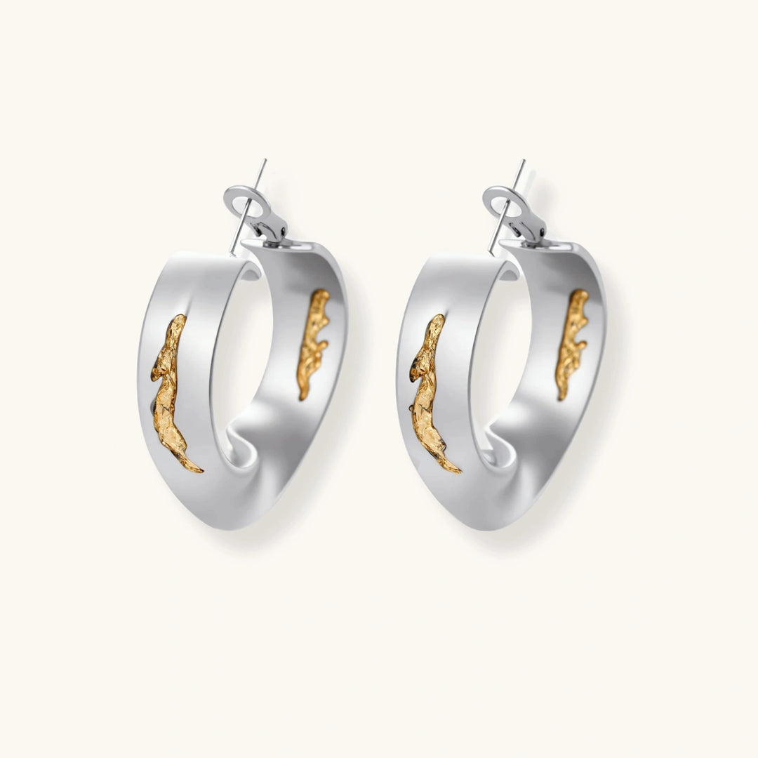 Artistic jewelry set featuring curved silver pendant with gold veining on black cord plus matching asymmetrical hoop earrings