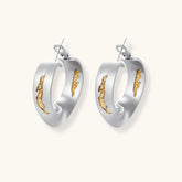 Artistic jewelry set featuring curved silver pendant with gold veining on black cord plus matching asymmetrical hoop earrings