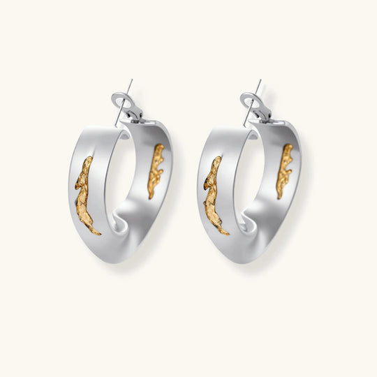 Artistic jewelry set featuring curved silver pendant with gold veining on black cord plus matching asymmetrical hoop earrings