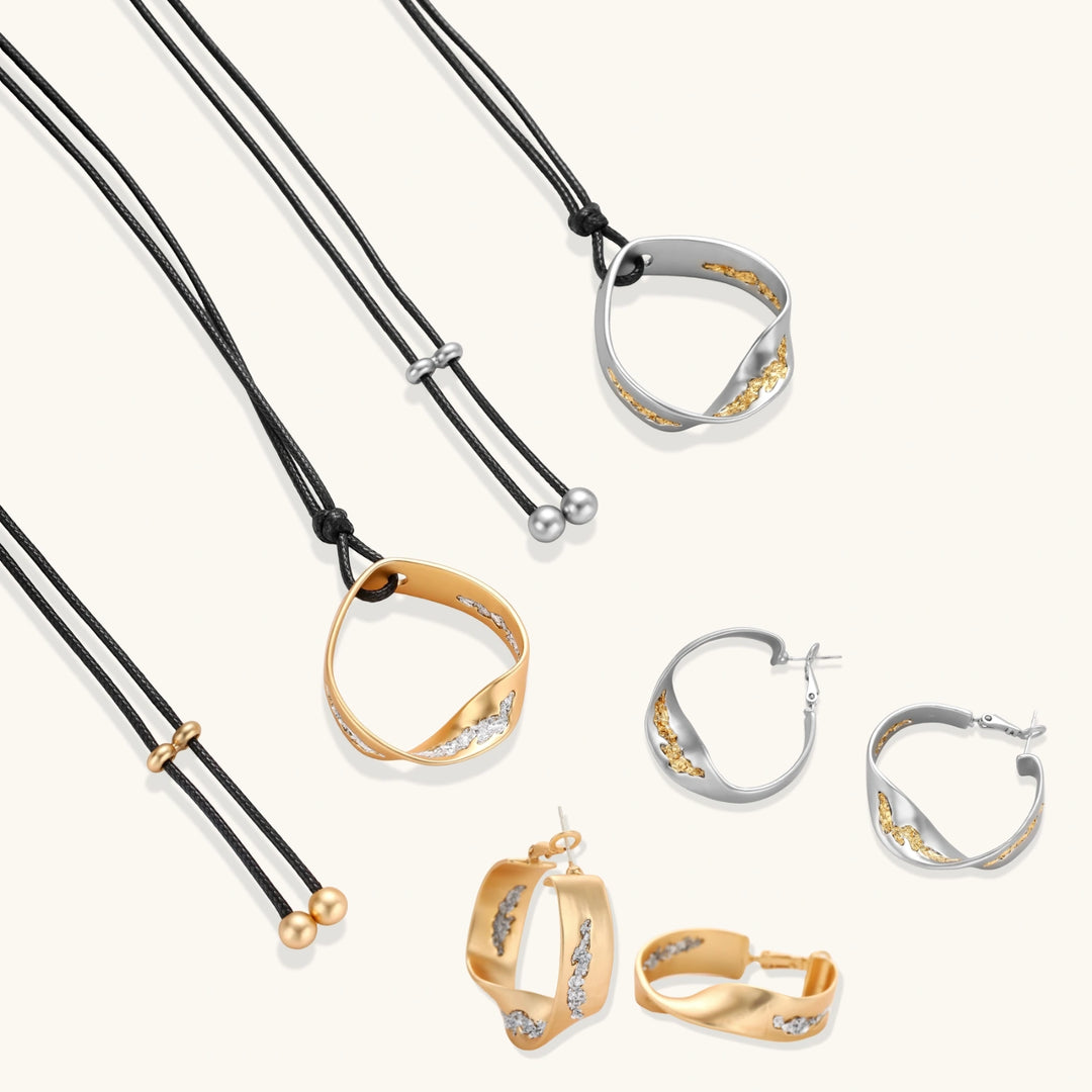Artistic jewelry set featuring curved silver pendant with gold veining on black cord plus matching asymmetrical hoop earrings