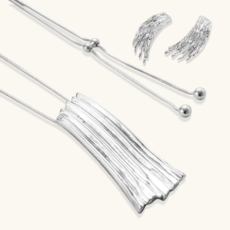 Layered metallic wing-shaped pendant and matching earrings with feathered texture in silver and gold finishes