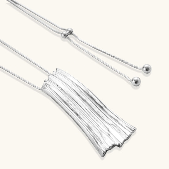 Layered metallic wing-shaped pendant and matching earrings with feathered texture in silver and gold finishes