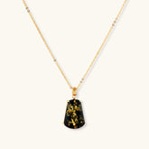 18k gold-plated necklace and earrings with green amber pendants featuring golden inclusions on cream background