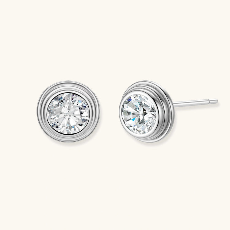 Close-up of sterling silver stud earrings featuring concentric circular frames with brilliant moissanite centers