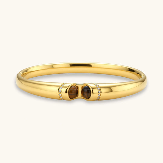 Polished gold bangle with two oval tiger's eye cabochons flanked by pavé diamond accents at center clasp.
