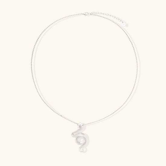 Abstract S-curve sterling silver pendant with zirconia accents on delicate chain against white background