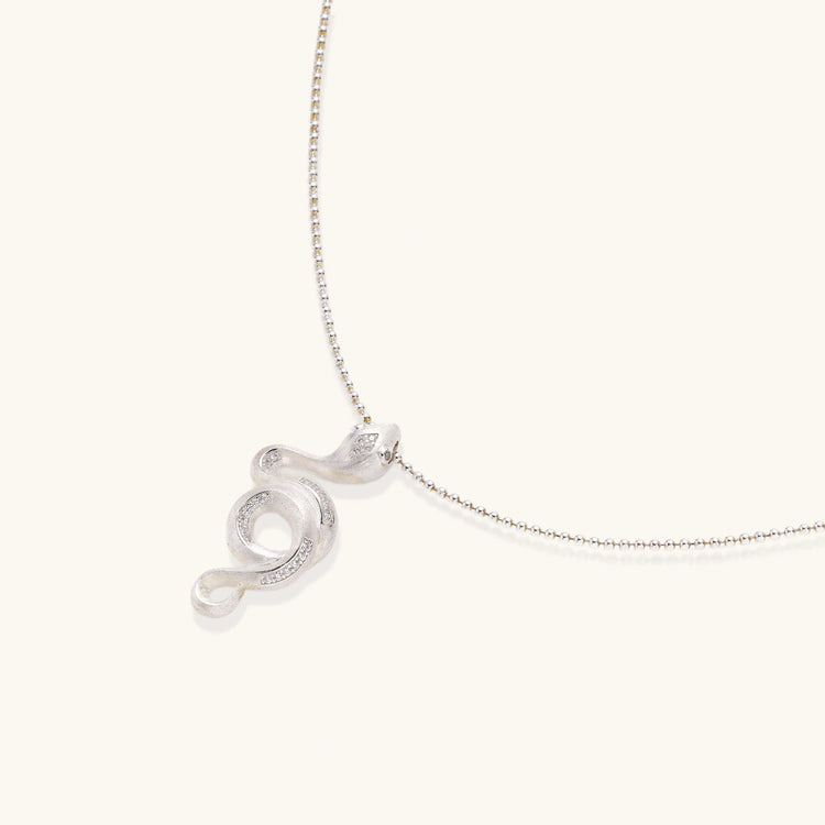 Abstract S-curve sterling silver pendant with zirconia accents on delicate chain against white background